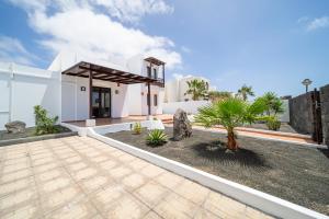 a white house with a courtyard with a palm tree at Villa Turquesa in Playa Blanca