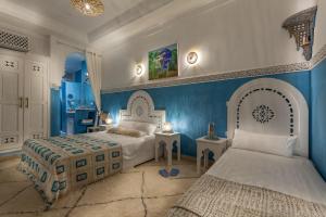 una camera da letto con due letti e una parete blu di Astra Damus Hotel a Marrakech