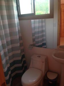 baño con aseo y lavabo y ventana en Cabañas del Faro, en El Peñón