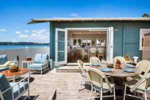 a patio with a table and chairs on a deck at Beachfront Bliss - Stay Waiheke in Onetangi
