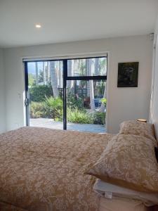 a bedroom with a large bed with a large window at Mangawhai Palms in Mangawhai