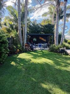 a backyard with palm trees and a table and chairs at Mangawhai Palms in Mangawhai