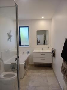 a bathroom with a sink and a tub and a toilet at Mangawhai Palms in Mangawhai +15 photos