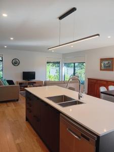 a kitchen with a sink and a living room at Mangawhai Palms in Mangawhai