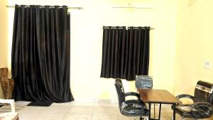 a room with black curtains and a table and a chair at The Stay Spot in Kharar