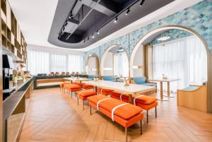 a waiting room with orange chairs and a table at Manxin Hotel Suzhou Jinfeng Road in Suzhou