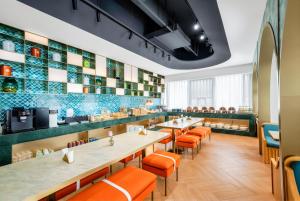 a restaurant with long tables and orange chairs at Manxin Hotel Suzhou Jinfeng Road in Suzhou