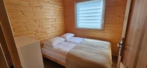 a small room with a bed in a wooden cabin at Perłowy Port in Gąski