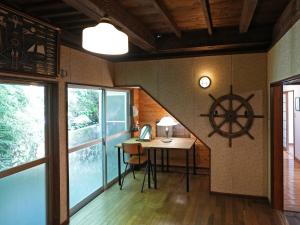 a room with a table and a ship wheel on the wall at Ukiwa Guest House in Shimoda
