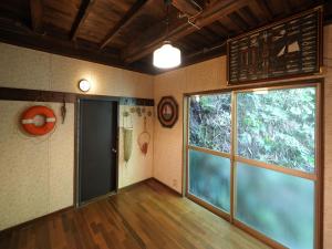 an empty room with a large window and a door at Ukiwa Guest House in Shimoda