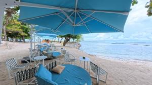 a beach with tables and chairs and blue umbrellas at Tambuli Seaside Living Pad seaview in Maribago