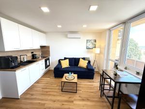 a living room with a blue couch and a kitchen at Sky View Apartmán 10 patro in Břeclav