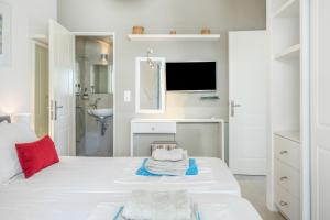 a white room with a bed and a sink and a tv at Beachfront Ios Villa in Ios Chora