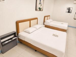 two beds in a small room with white walls at Allisa Resort Hotel in Anyer