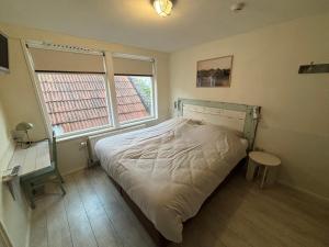 a bedroom with a bed and a desk and a window at Hotel B&B Altijd Wad in West-Terschelling