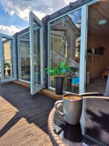 a deck with sliding glass doors and a cup of coffee at Pool Hause Palanga in Palanga