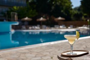 a martini glass sitting on a table next to a pool at Ariti Grand Hotel in Corfu