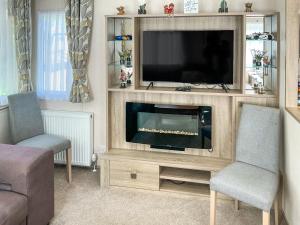 a living room with a television and two chairs at Maggie's Place in Dunkeld