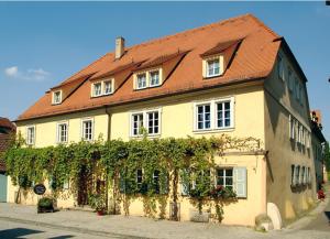 ein großes gelbes Haus mit rotem Dach in der Unterkunft Weingut Gästehaus Weigand in Iphofen