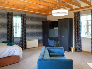 a bedroom with a bed and a blue couch and a chair at The Studio Cottage in Knock +6 photos