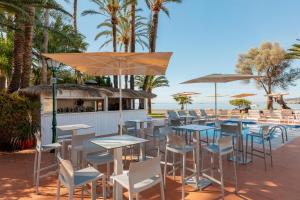 a restaurant with tables and chairs and a beach at THB Los Molinos - Adults Only in Ibiza Town