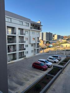 a parking lot with cars parked in front of a building at M&M Nest in Windhoek