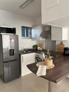 a kitchen with white cabinets and a table with a bottle of wine at M&M Nest in Windhoek