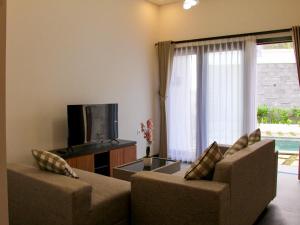 a living room with a couch and a tv at Mimpi Ayung Villas by AGATA in Bringkit +21 photos