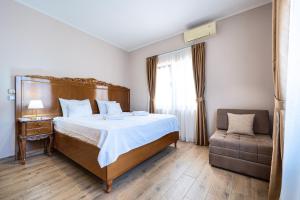a bedroom with a bed and a chair and a window at Hotel Perun in Budva