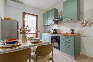 a kitchen with green cabinets and a table with chairs at Appartamenti Da Ewa Valledoria in Valledoria