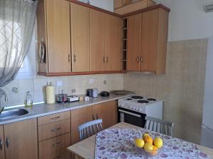 a kitchen with wooden cabinets and a table with a bowl of fruit at Aspasia's apartment in Mytilene