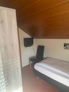 ein Schlafzimmer mit Bett, Stuhl und Fernseher in der Unterkunft Hotel-Windeck in Burbach + 30 Fotos