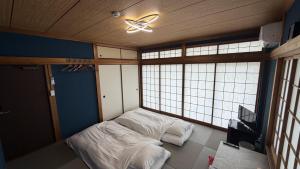 a room with two beds and a ceiling fan at hostel大黒屋 in Miyoshi