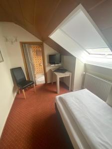 ein Zimmer mit einem Bett, einem Schreibtisch und einem Fernseher in der Unterkunft Hotel-Windeck in Burbach