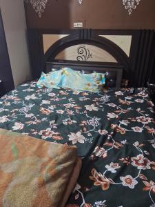 a bed with a blanket with flowers on it at Radhe house in Gwalior