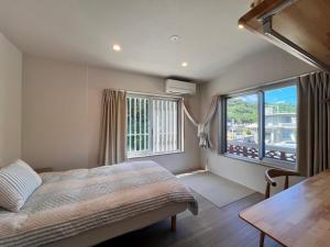 a bedroom with a bed and a large window at Beachside Pension Mibal in Nanjo