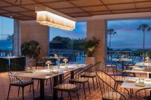 a dining room with tables and chairs and a large window at Sarena de Muro Resort Mallorca, part of Destination by Hyatt in Playa de Muro