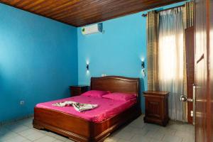 a bedroom with a bed with pink sheets and blue walls at Résidence Jeanne à Yaoundé Odza Messamengo in Yaoundé