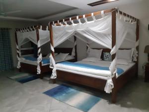 two beds in a bedroom with a canopy at Villa HASSANI BEACH FOULPOINTE in Foulpointe +69 photos