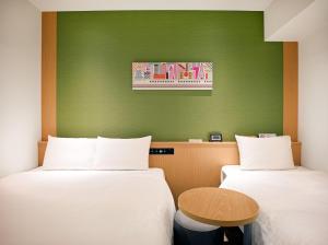 two beds in a room with a green wall at SONO Moon Nagoya in Nagoya