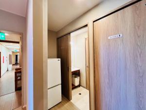 a room with a refrigerator and a hallway at Beachside Pension Mibal in Nanjo