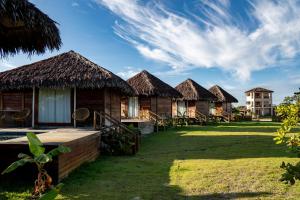 a row of cottages with grass roofs at Pacas Suítes Lençóis Eco Lodge in Santo Amaro