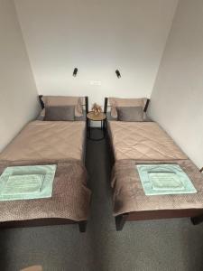 two beds in a small room with a table between them at 208 Apartment Ania in Koszalin