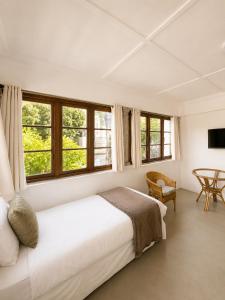 a bedroom with a bed and a table and windows at 12 On Braemar Guesthouse in Cape Town
