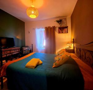 a bedroom with a bed with a blue blanket at La Maison des Oiseaux in Crouzilles