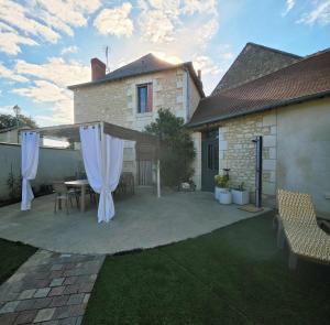 a patio with a table and white curtains at La Maison des Oiseaux in Crouzilles