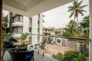 a balcony with a table and chairs and a building at Go Offline Homes - Designer 2BHK with Pool Near Candolim in Parra