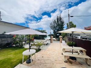 a patio with two tables and two umbrellas at Beachside Pension Mibal in Nanjo