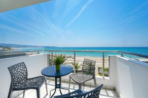 a balcony with a table and chairs and the ocean at OzioMari Suites in Limenaria