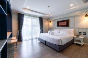 a bedroom with a white bed and a large window at Rimwiang in Chiang Mai